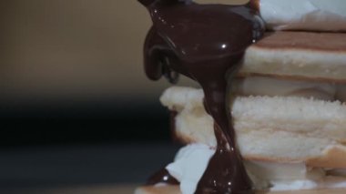 Pişirme krepinin yakın çekimi. Aşçı tatlıya sıcak çikolata şurubu döker.