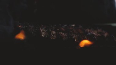 Barbekü pikniği caddenin dışında. Izgarada ateşte kızartılmış pirzola ve dumanla yakın çekim. Biftek soslu fırçayla kaplıdır. Büyük bir arkadaş grubu için yazın leziz ızgara et.