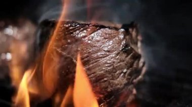 Izgarada yanan kömürde sulu bir biftek kızartıyorum. Izgarada şeritli sulu biftek, piknik kutlaması için hazır. Barbekü ızgarası dışarıda. yavaş çekim