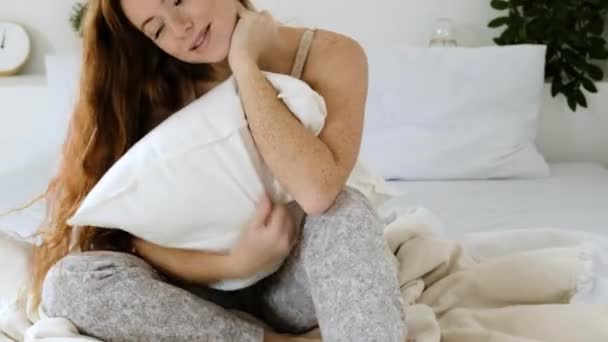 머리를 행복하고 아름다운 여자가 침대에서 부드러운 베개를 움켜쥐고 잠옷을 아침을 — 비디오