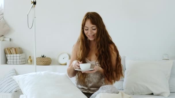 Jonge Vrouw Drinkt Koffie Zit Wit Bed Glimlacht Goede Morgen — Stockvideo