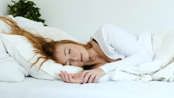 美丽的红头发姑娘静静地躺在房间里明亮的床上 卧室里的枕头上铺着毛毯 睡着了 周末安安静静睡在舒适的床上 — 图库视频影像