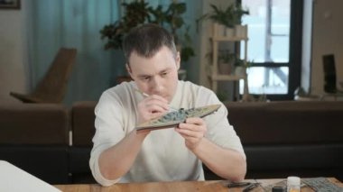 Çizimler ve talimatlara göre savaş gemisinin mutlu yetişkin erkek derleyici plastik modeli. Adam tasarım elemanlarını fırçayla boyuyor. Çocukluk hayalinin vücut bulmuş hali. Geniş Ölçekli Modelleme