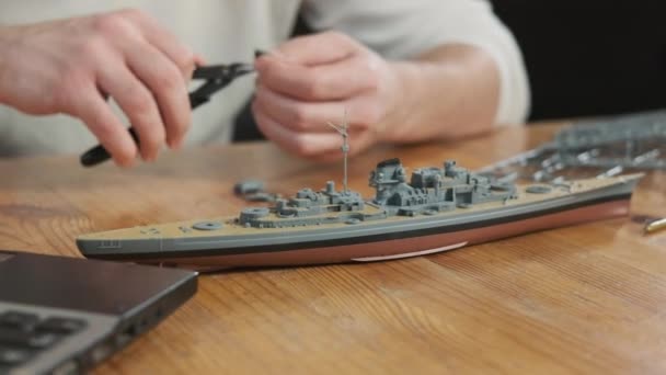 人装配工在桌旁的房间里建立塑料船舶模型 用工具建立玩具和螺丝元件模型 对建模和制作玩具的热情 童年梦想的体现 — 图库视频影像