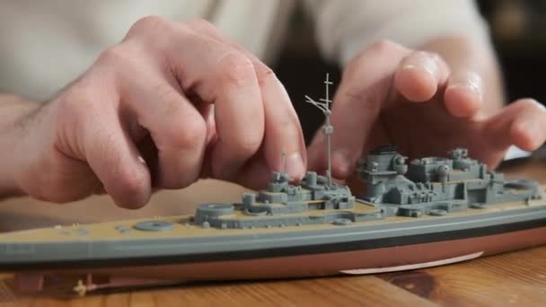 根据图纸和说明制作的快乐的成年男装塑料战舰模型 用双手粘贴元素排布的人的身体 对建模和制作玩具的热情 比例建模 — 图库视频影像