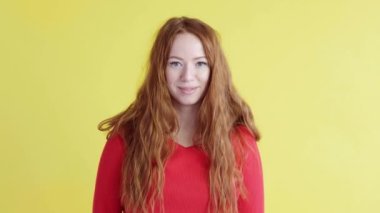 Sarı arka planda gülümseyen mutlu bir kadının portresi. İnsanların olumlu duyguları. Özgürlük için. Kızıl saçlı kadın kameraya bakar ve gülümser. Hoş kız.