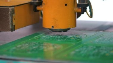 Yüksek teknoloji ürünü robotik ekipmanlara yakın çekim. PCB montajı. Ana kartın CNC makinesi üzerindeki modern teknolojik etkisi. Fabrikanın dijital sektöründe üretim süreci.