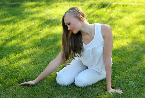 Jovem mulher acariciando a grama — Fotografia de Stock