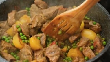 Kadın eli, et güveci pişirirken patatesle yakın plan, ev yapımı yemekler.