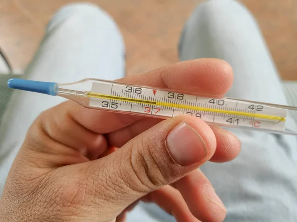 Man hold a Mercury fever thermometer after measurement,coronavirus covid19 pandemic — Stock Photo, Image