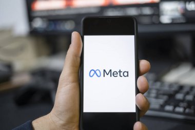 Genç adam akıllı telefonunda yeni bir Meta uygulaması kullanıyor, Facebook yeniden markalaştırma logosu, metaverse uygulamaları