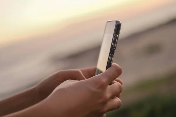 Jovem mulher usar smartphone para bate-papo de mídia social sobre fundo por do sol, vício em células, tecnologia nova era — Fotografia de Stock