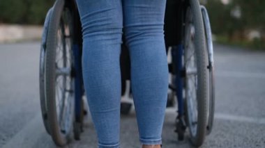 Bakıcı kadın, tekerlekli sandalyedeki felçli çocuğa dışarıda manzara ve sağlık hizmetlerinde yardım ediyor. 