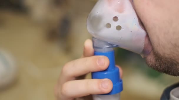 Человек использует медицинский аэрозольный ингалятор для лечения респираторных вирусов, пандемических заболеваний здравоохранения — стоковое видео