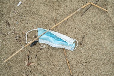 Deniz kıyısındaki ekosisteme atılmış cerrahi yüz maskesi, 19 salgın hastalık atığı.