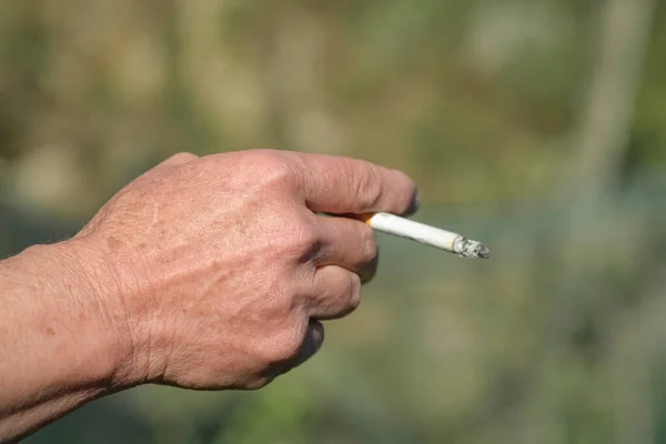 Eldre kvinner holder brennende sigaretter mens de røyker, tobakksrøyker, usunn hudskade livsstil – stockfoto