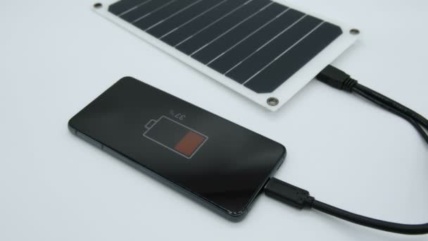 Вид зарядки смартфона с помощью портативной солнечной фотоэлектрической панели, возобновляемые технологии зеленой энергии — стоковое видео