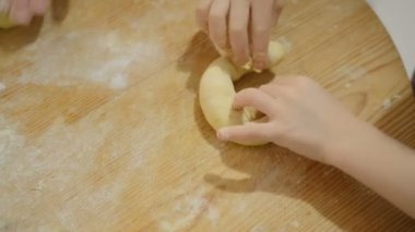 Çocuk kızı, evde el yapımı hamur işleri hazırlamak için annesiyle hamur yoğurur.