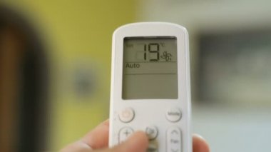 Klima termostat ev sıcaklığını ayarlarken insan eli, elektrik atığı
