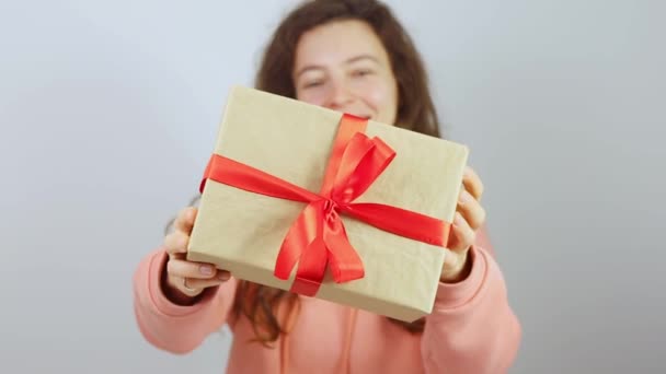 Giovane donna felice in possesso e sorridente dando giftbox con nastro rosso e fiocco. Congratulazioni con San Valentino, anniversario di compleanno, dichiarando amore e mostrando attenzione.Filmati FullHD di alta qualità — Video Stock