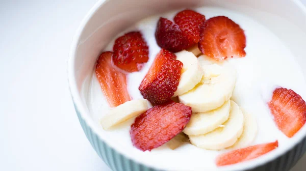 Close up white natural greek yogurt cream with fresh juicy strawberry and sliced banana in round bowl on white background. Top view. Healthy breakfast from nutritionist, good for digestion. — Stock Photo, Image