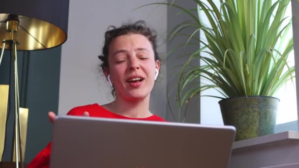 Izgatott fiatal nő mosolyog beszél videohívás segítségével laptop ül beltérben a modern belsőben.Chatting miután kellemes online beszélgetés barátjával, szülő segítségével 5g vezeték nélküli internet kapcsolat — Stock videók