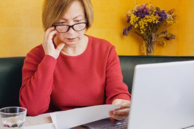 Evde otururken beklenmedik haberler karşısında şaşıran endişeli, olgun bir kadın gazete okuyor ya da posta mektubu yazıyor. Alınan banka hesabı bakiyesi ya da kötü uyarı, iyi, iflas