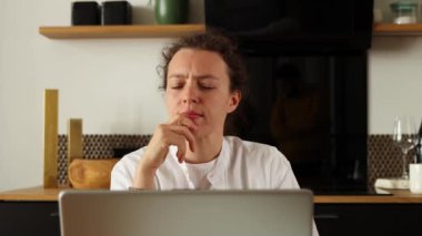Genç beyaz kadın dizüstü bilgisayarda çalışıyor, uzaktan bağımsız işler yapıyor, evde oturuyor, düşünceli görünüyor, sorunları düşünüyor, iş sorunlarını çözüyor, beyaz gömlek giyiyor. Yaratıcı beyin işi konsepti.