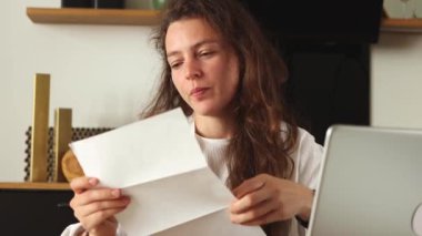 Happy young caucasian woman reading papper letter about college admission, scholarship approved, invitation for internship abroad, sit with laptop at home.Got hired job of dream,celebration of victory