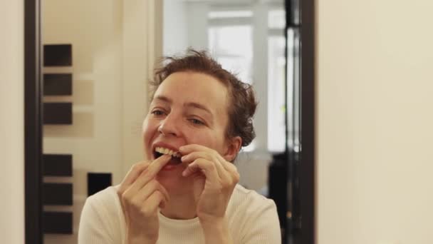 快乐迷人的年轻白人女人在浴室用牙线刷牙 照镜子 早餐后去掉食物 保健治疗和口腔卫生概念 — 图库视频影像