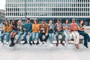 Şehirdeki bir grup genç insan sokakta oturan cep telefonunu kullanıyor - z gen gençliği sosyal ağ tarafından absorbe ediliyor - yaşam tarzı teknolojisi kavramı - internete bağlı kızlar ve erkekler