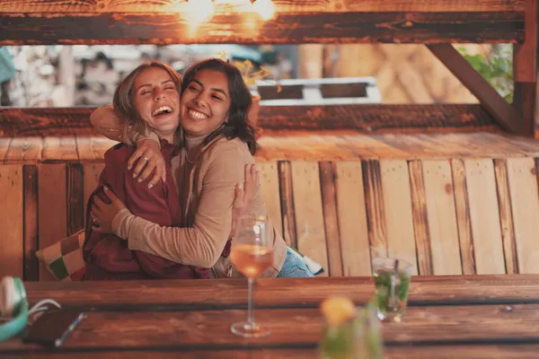 İki bayan arkadaş, mutlu bir şekilde sarılıyorlar.