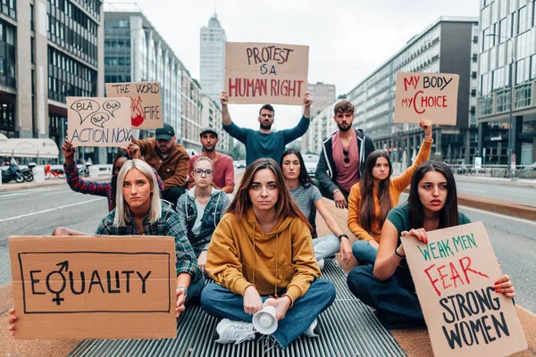 group of young people holding protest banners in a march for the woman rights and gender equality