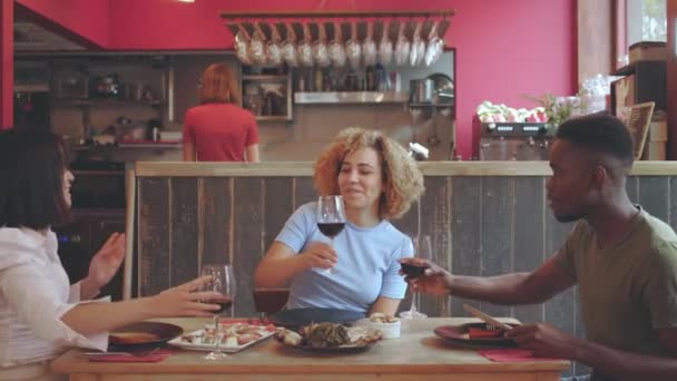 レストランでワインで乾杯する仲間たち テーブル席に座って食事を楽しむ若者たち — ストック動画