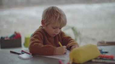 blond child coloring on a sheet