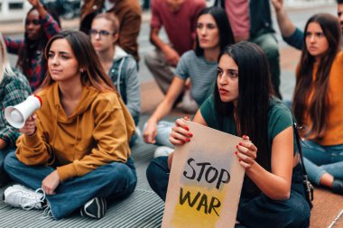Ukrayna 'da barışı protesto etmek için sokakta oturan bir grup genç - savaş metni olmayan karton ve Ukrayna bayrağı renkleri