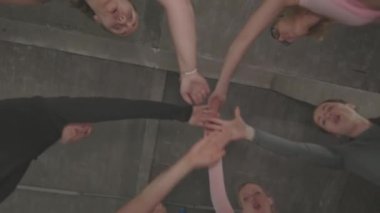 Çemberde bir grup kadın sporcunun el ele tutuşup birlik içinde el ele tutuşmalarının alttaki görüntüsü.