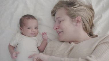 Mutlu anne ve yeni doğmuş bebek - anne ve çocuk yatakta kucaklaşıyorlar.