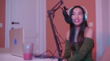 Kadın canlı yayında mikrofona konuşuyor. Asyalı kız podcast yapıyor.