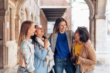 female friends speaking together - girls having fun outdoor - multiethnic women having weekend in the city center