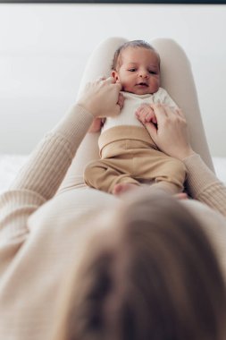 Annesinin bacaklarındaki küçük bebek - dikey fotoğraf