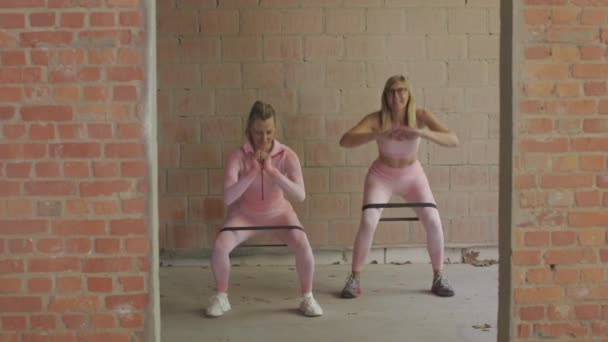 Δύο Λευκές Γυναίκες Ροζ Αθλητικές Φόρμες Κάνουν Καταλήψεις Λαστιχάκι Εσωτερικούς — Αρχείο Βίντεο