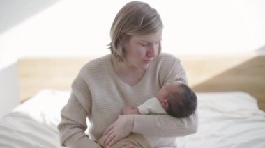 Mutlu bir anne kucaklıyor, kucaklıyor ve yeni doğmuş bebeğiyle odada bağ kuruyor. Anne ile yeni yürümeye başlayan bebek ilişkisi.