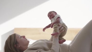 Anne yatakta uzanıp bebeğiyle öpüşüyor ve bağ kuruyor.