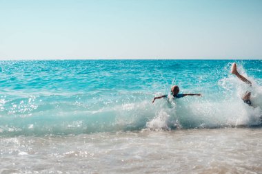 İnsanlar, okyanusun turkuaz dalgalarında, cennet gibi deniz manzarası renklerinde oynuyorlar.