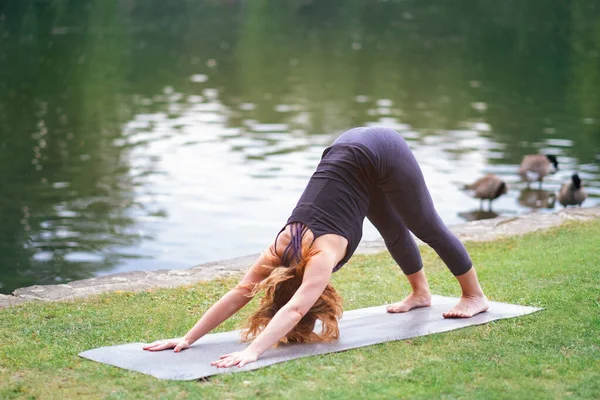 sporty lady doing yoga outdoor at park nearby water