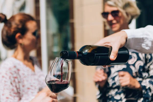 pouring red wine on glass at the aperitif happy hour wine tasting