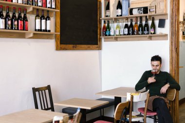 Şarap imalathanesi sahibi şarap ve tahtanın altında oturmuş şarap kokusu alıyor.