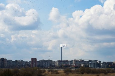 Bükreş, Romanya - 10 Mart 2022: Bükreş 'in güneyinde pek çok apartman bloğunun üzerinde görüldüğü üzere, ısınma yağı ve gazlarından çıkan dumanla kirlenen CET Progresul enerji santralinin bacası