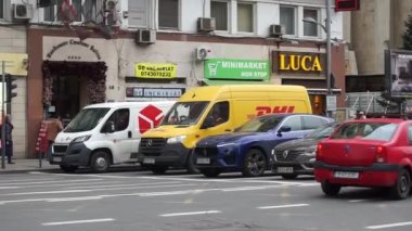 Bükreş, Romanya - 09 Mart 2022: Bükreş 'teki Nicolae Balcescu Bulvarı' ndaki trafikten hızla geçen sarı bir DHL teslimatı. Bu resim sadece editörler içindir..